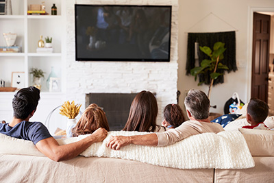 Vacationers sitting on comfortable couch looking at flat screen TV in Seaside Park rentals